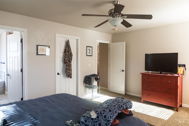 bedroom with ensuite bathroom, light carpet, and ceiling fan