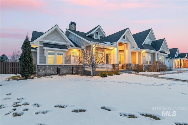 view of front of home featuring stone siding, a fenced front yard, and a chimney