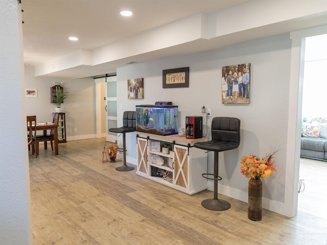 bar featuring light hardwood / wood-style flooring and a barn door