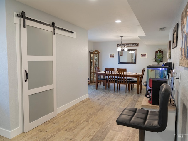 dining room with a barn door and light wood-type flooring