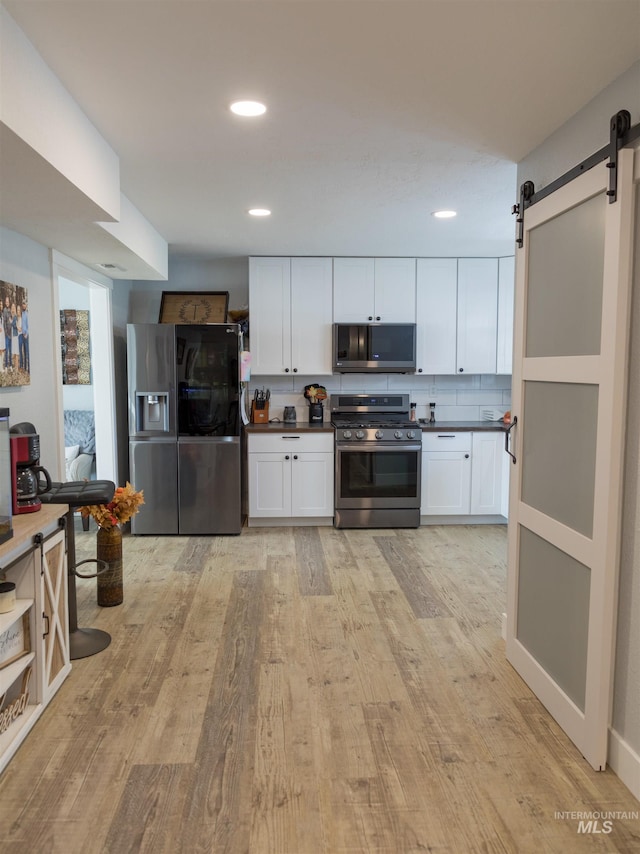 kitchen featuring white cabinets, stainless steel appliances, and a barn door