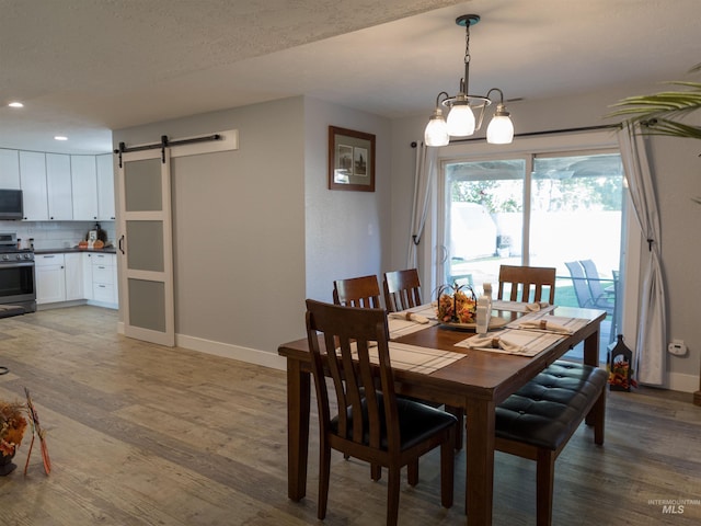 dining area with a textured ceiling, a barn door, a chandelier, and dark hardwood / wood-style flooring