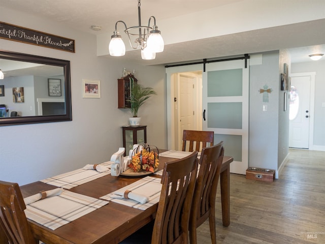 dining space with an inviting chandelier, dark hardwood / wood-style floors, and a barn door