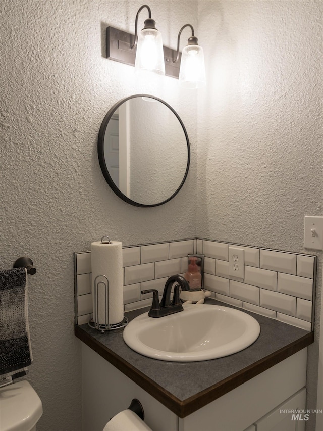 bathroom with vanity, decorative backsplash, and toilet