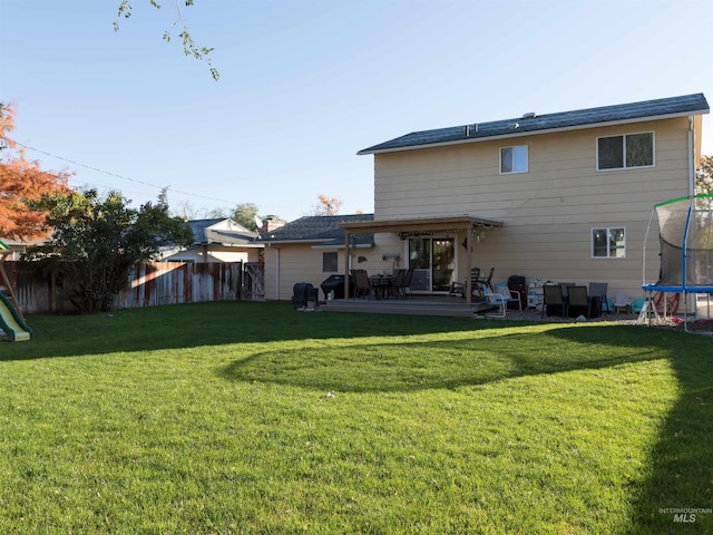 back of property featuring a patio, a lawn, and a trampoline