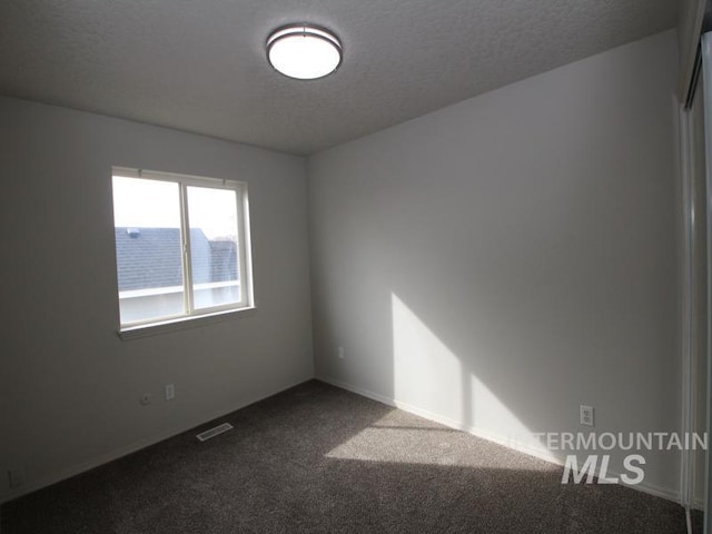 carpeted empty room with visible vents and a textured ceiling