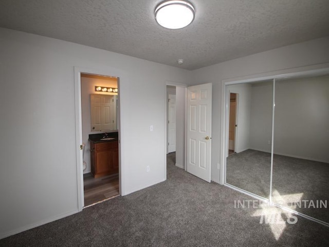 unfurnished bedroom with carpet floors, a textured ceiling, connected bathroom, and a closet