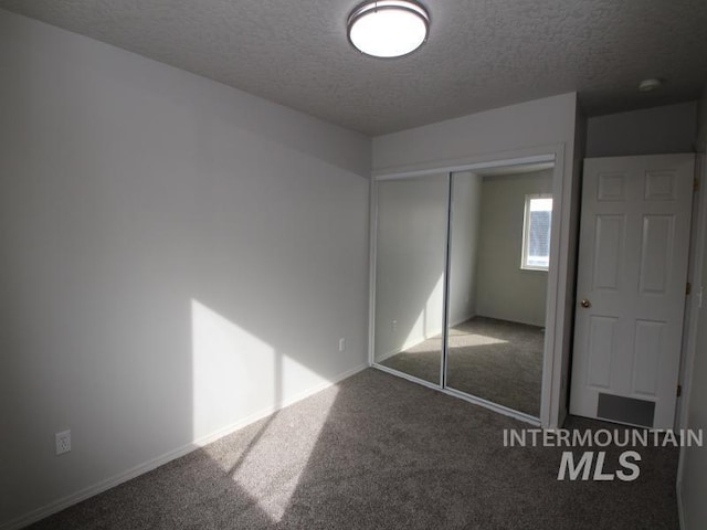 unfurnished bedroom with a textured ceiling, a closet, and carpet