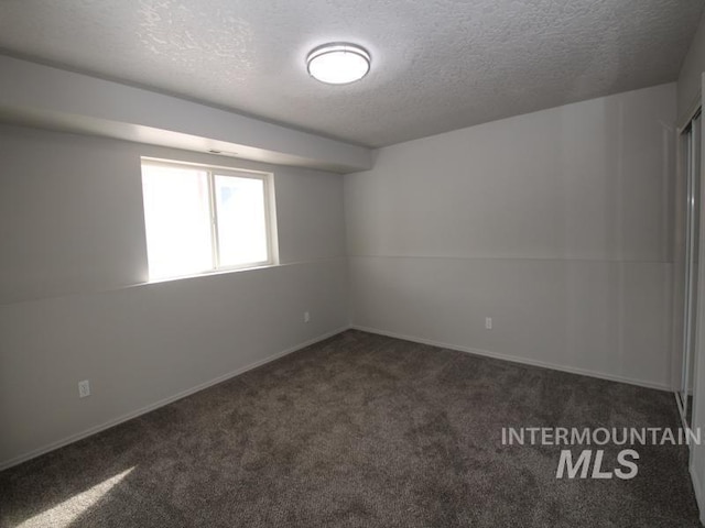 spare room with dark colored carpet and a textured ceiling