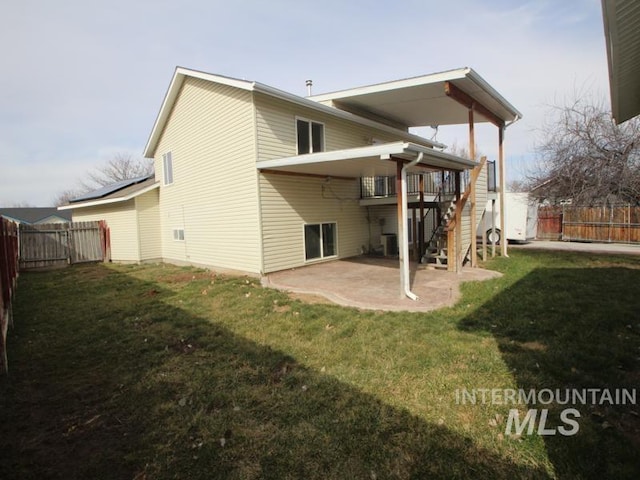 rear view of property featuring a patio, stairway, a fenced backyard, and a lawn