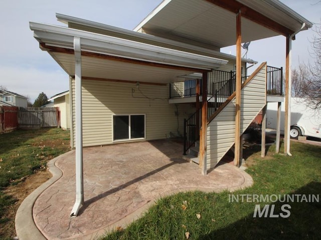 back of house featuring a patio area, fence, a lawn, and stairs