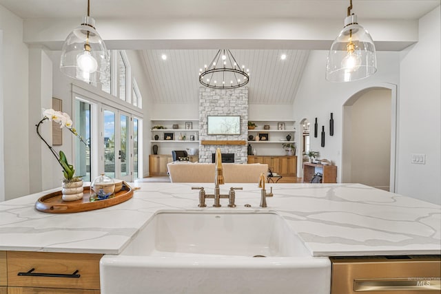 kitchen featuring built in features, a fireplace, arched walkways, a sink, and open floor plan