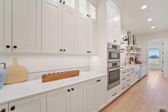 kitchen with white cabinets, double oven, light wood-style flooring, and open shelves