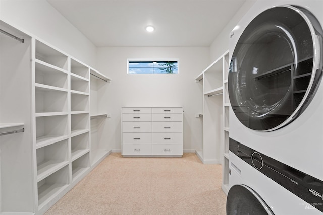 clothes washing area with baseboards, light carpet, laundry area, and stacked washing maching and dryer