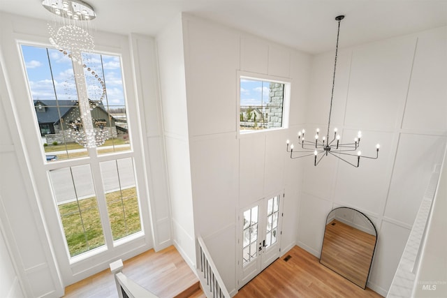 entrance foyer with light wood finished floors, visible vents, a decorative wall, and an inviting chandelier