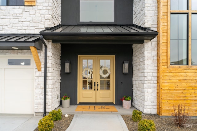 doorway to property with a garage, metal roof, a standing seam roof, and stone siding