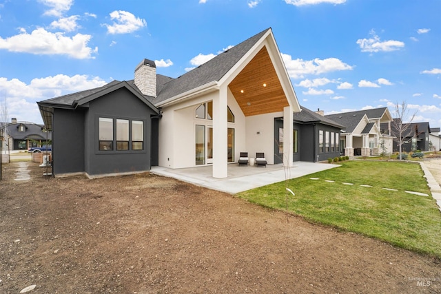 rear view of property with a patio, a yard, a chimney, stucco siding, and a residential view