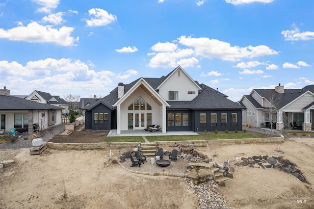 rear view of house with an outdoor fire pit, french doors, a shingled roof, a chimney, and a patio area