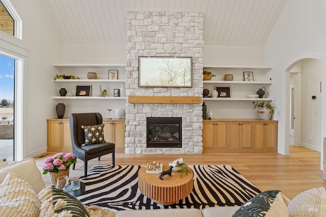 living area featuring built in features, arched walkways, wooden ceiling, and wood finished floors