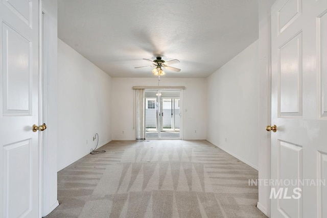 empty room featuring baseboards, a ceiling fan, and light colored carpet