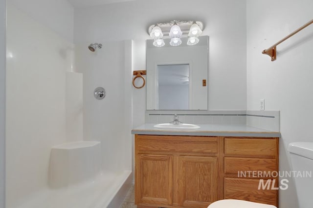 bathroom featuring vanity, tasteful backsplash, walk in shower, and toilet