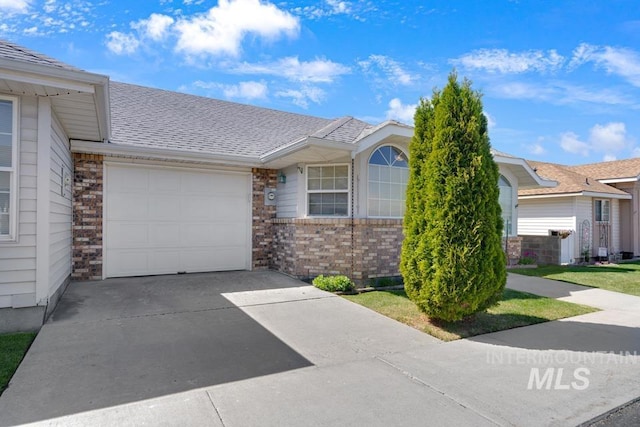 single story home with a garage, concrete driveway, roof with shingles, and brick siding