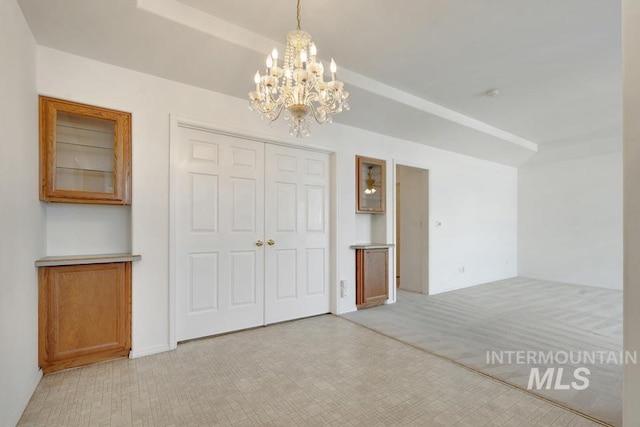 unfurnished bedroom featuring light colored carpet, a notable chandelier, and a closet