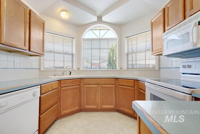 kitchen featuring a sink, light countertops, tasteful backsplash, and white appliances