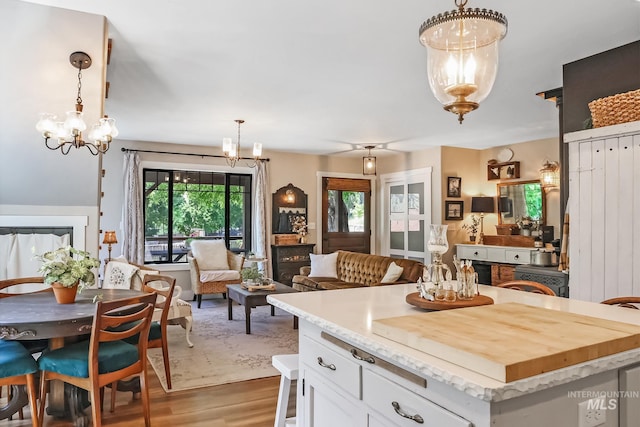 kitchen featuring white cabinetry, a kitchen island, hanging light fixtures, and light wood-type flooring