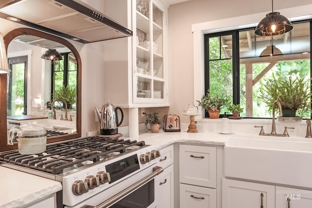 kitchen featuring white cabinetry, sink, stainless steel gas range, and a healthy amount of sunlight