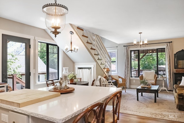 dining room with a wealth of natural light, lofted ceiling, hardwood / wood-style floors, and a notable chandelier