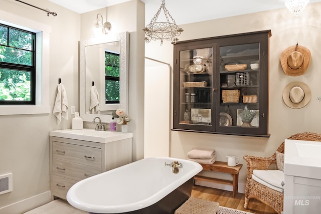 bathroom with hardwood / wood-style floors, vanity, a washtub, and an inviting chandelier