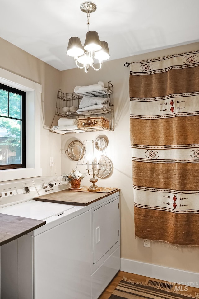 laundry area with separate washer and dryer, hardwood / wood-style flooring, and a chandelier