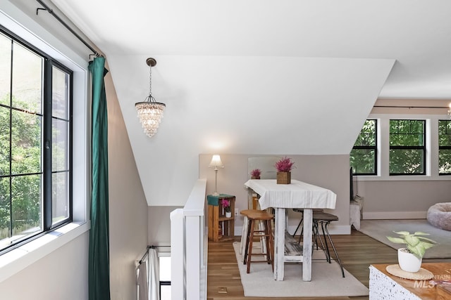 dining room featuring wood-type flooring, vaulted ceiling, and an inviting chandelier