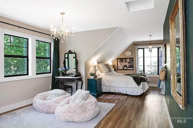 bedroom featuring lofted ceiling, hardwood / wood-style floors, and a notable chandelier