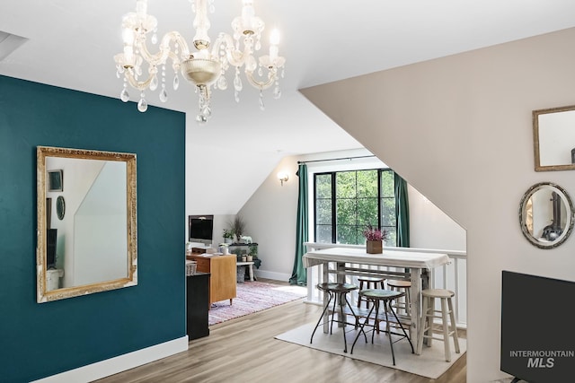 dining room featuring hardwood / wood-style flooring, vaulted ceiling, and a notable chandelier