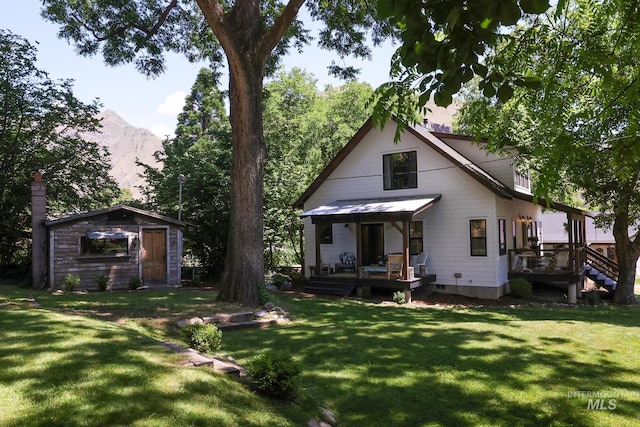 rear view of house with a storage unit, a mountain view, and a lawn