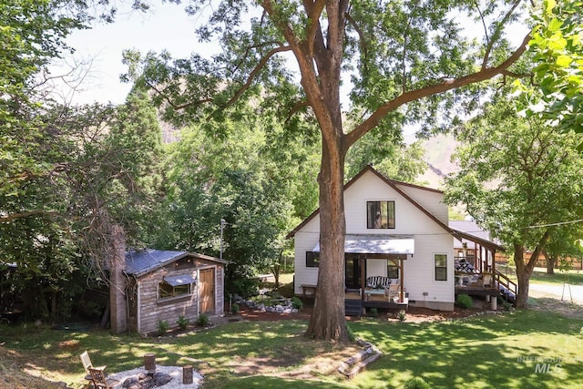 rear view of house with a yard, an outdoor fire pit, and a shed