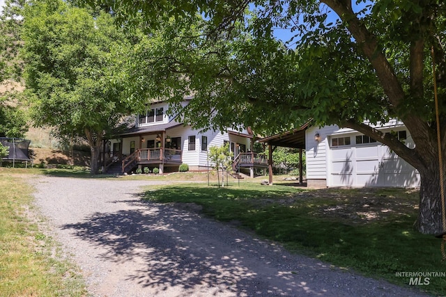 view of front of property featuring a garage, an outdoor structure, a trampoline, and covered porch