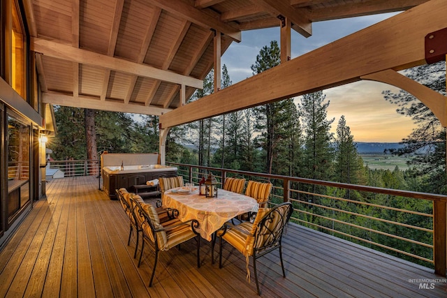 deck at dusk featuring a hot tub