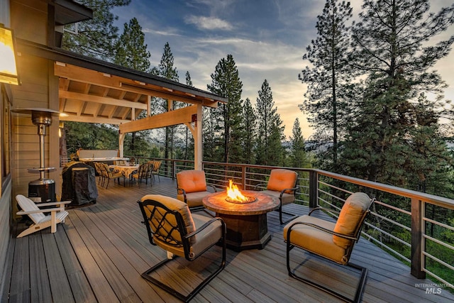 deck at dusk featuring an outdoor fire pit