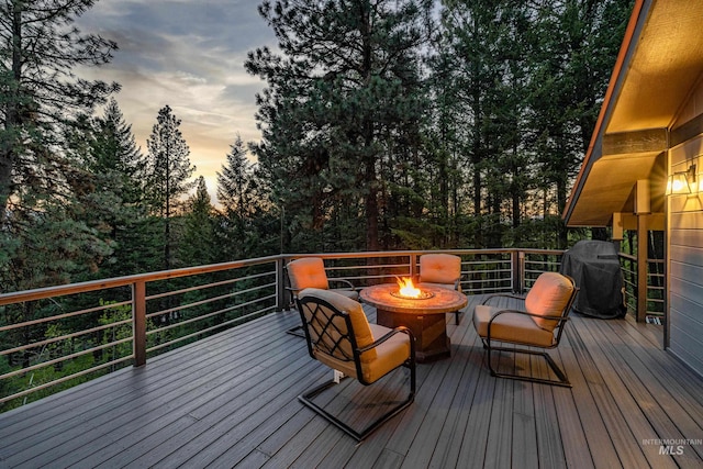 deck at dusk with a fire pit and a grill