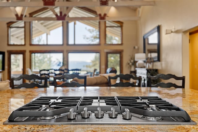 kitchen featuring beam ceiling, a towering ceiling, and light stone counters