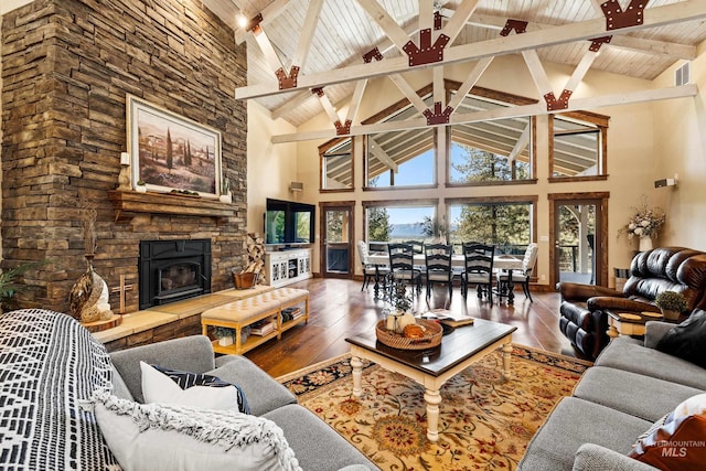 living room with beamed ceiling, hardwood / wood-style floors, a stone fireplace, high vaulted ceiling, and wood ceiling