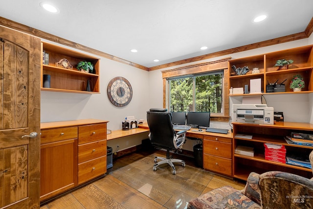 office space with dark wood-type flooring, built in desk, and crown molding