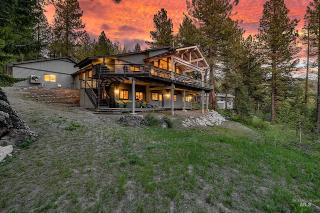 back house at dusk with a lawn and a wooden deck