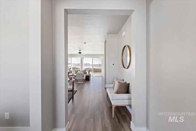 hall with wood finished floors and a textured ceiling