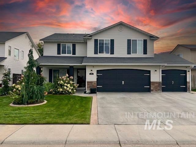 view of front of property featuring concrete driveway, a garage, a front yard, and stone siding