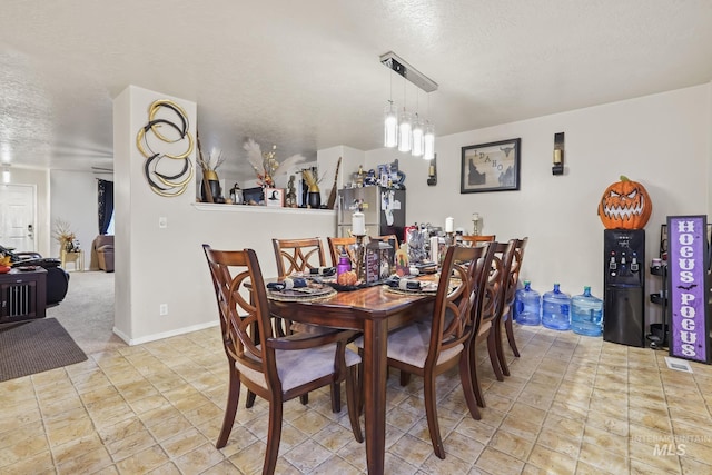 dining room featuring a textured ceiling and baseboards