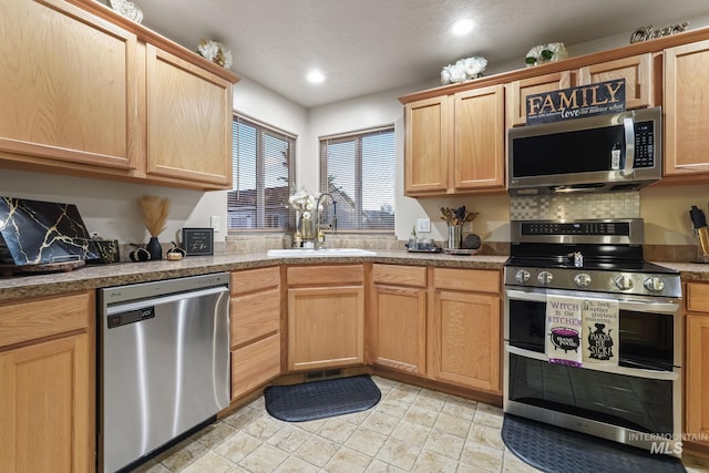 kitchen with decorative backsplash, light brown cabinets, stainless steel appliances, and a sink